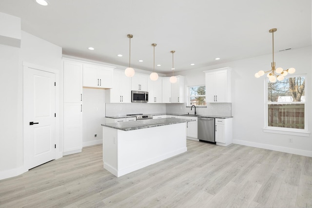 kitchen featuring decorative light fixtures, a center island, white cabinets, and appliances with stainless steel finishes