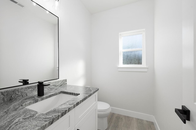 bathroom with toilet, vanity, and hardwood / wood-style flooring