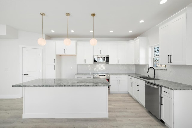 kitchen featuring sink, stainless steel appliances, hanging light fixtures, and a center island