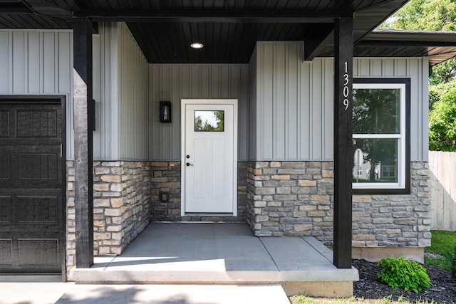 1309 E Blaine St, Springfield, MO 65803 - view of exterior entry with stone siding, board and batten siding, a porch, and an attached garage