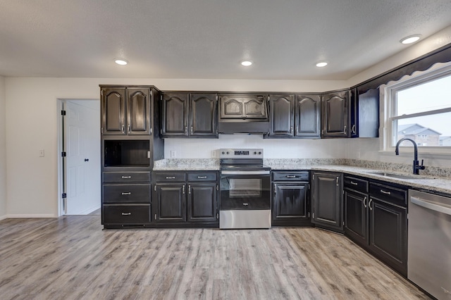 kitchen featuring stainless steel appliances, light wood-type flooring, light stone countertops, decorative backsplash, and sink