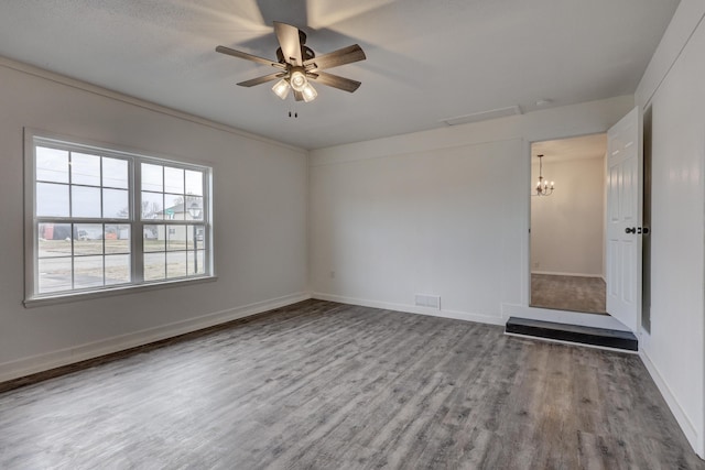 empty room featuring ceiling fan with notable chandelier and hardwood / wood-style floors