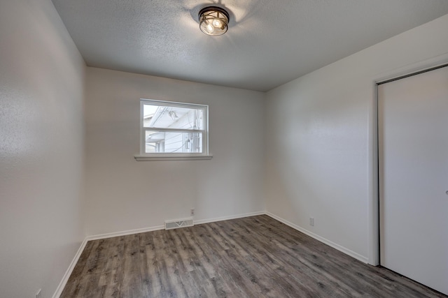 empty room featuring a textured ceiling and wood-type flooring