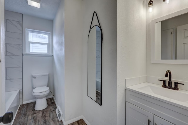 full bathroom with toilet, hardwood / wood-style flooring, a textured ceiling, bathing tub / shower combination, and vanity