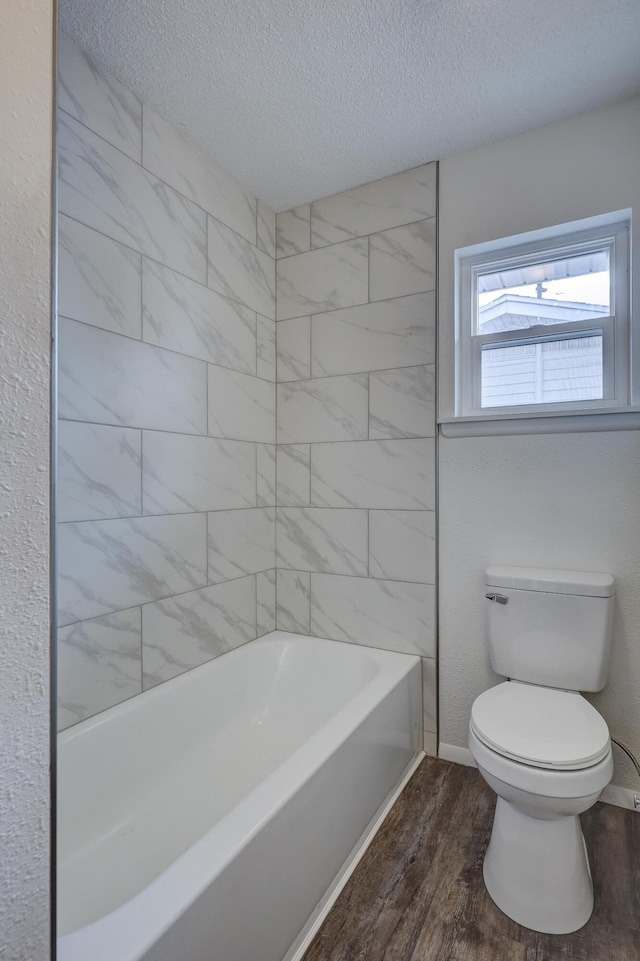 bathroom featuring a textured ceiling, shower / tub combination, toilet, and wood-type flooring