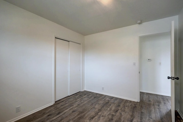 unfurnished bedroom featuring a closet and dark wood-type flooring