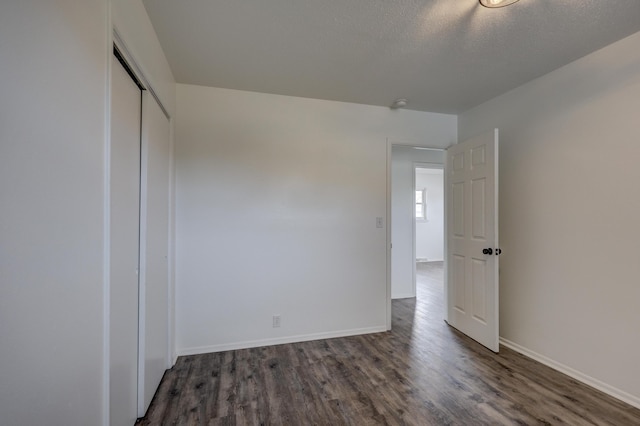 unfurnished bedroom with a textured ceiling, a closet, and dark hardwood / wood-style floors