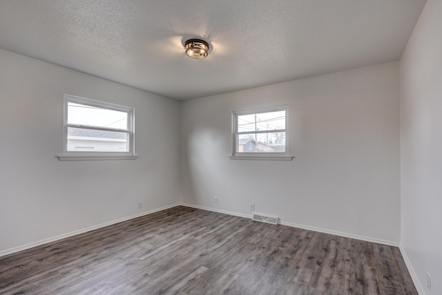 spare room featuring a textured ceiling and dark wood-type flooring