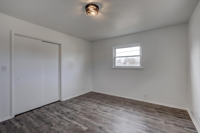 unfurnished bedroom with a textured ceiling, a closet, and hardwood / wood-style floors