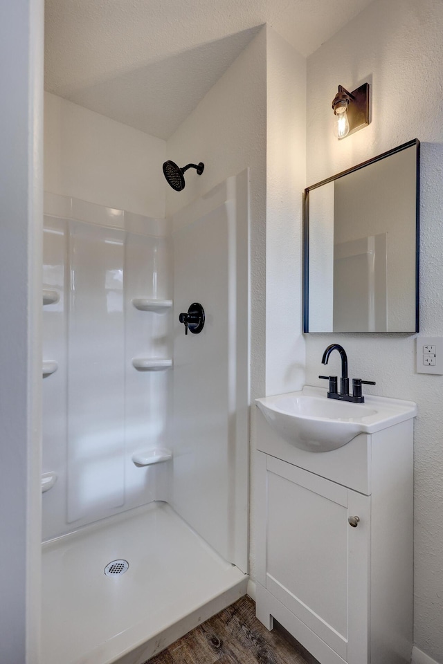 bathroom with walk in shower, hardwood / wood-style floors, and vanity