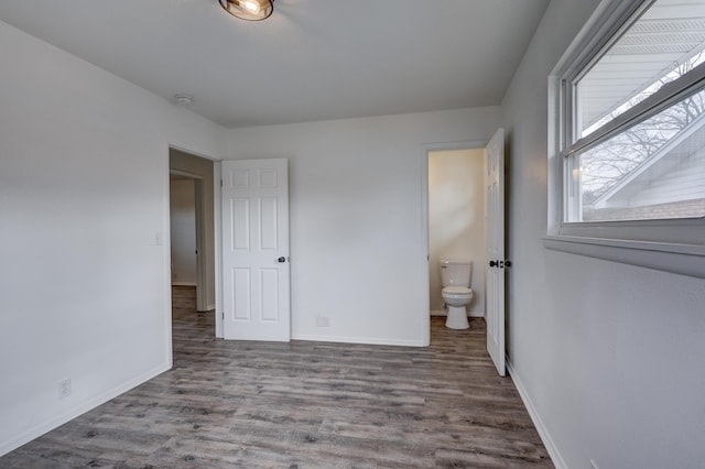 unfurnished bedroom with hardwood / wood-style flooring and connected bathroom