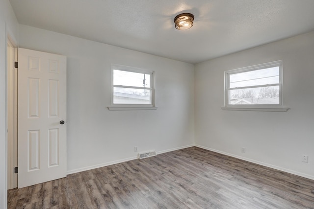 empty room with a textured ceiling and hardwood / wood-style flooring