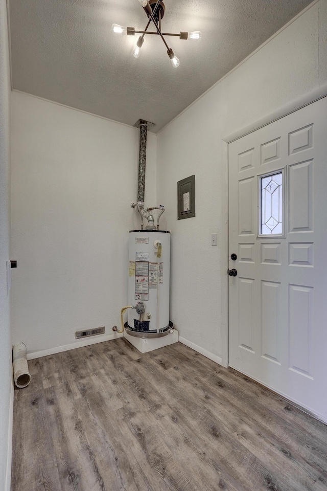 foyer with gas water heater, a textured ceiling, an inviting chandelier, and light hardwood / wood-style flooring