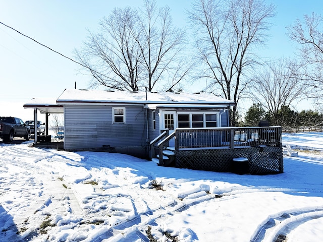 snow covered back of property with a deck