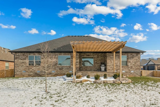 snow covered back of property with a pergola