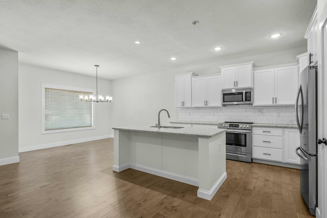 kitchen featuring stainless steel appliances, a center island with sink, white cabinetry, and sink