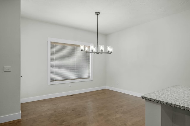 unfurnished dining area with an inviting chandelier and dark hardwood / wood-style floors