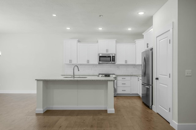 kitchen with sink, stainless steel appliances, white cabinetry, and a kitchen island with sink