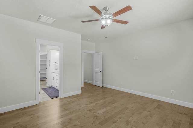 unfurnished bedroom with ceiling fan, a spacious closet, and light hardwood / wood-style flooring