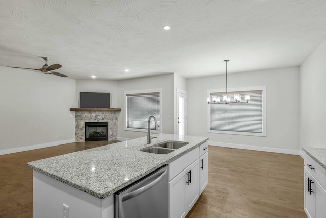 kitchen featuring sink, white cabinets, a fireplace, dishwasher, and hanging light fixtures