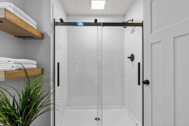 bathroom with a textured ceiling and a shower with shower door