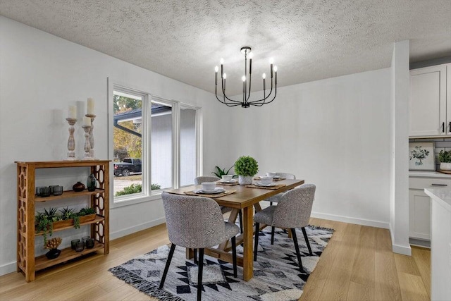 dining area featuring an inviting chandelier, light hardwood / wood-style flooring, a textured ceiling, and plenty of natural light