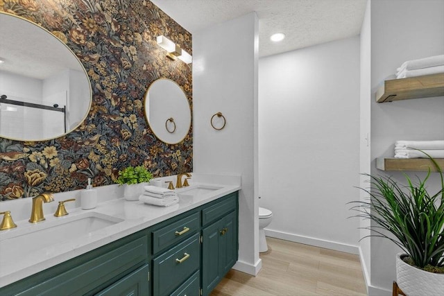 bathroom featuring toilet, a textured ceiling, hardwood / wood-style floors, an enclosed shower, and vanity