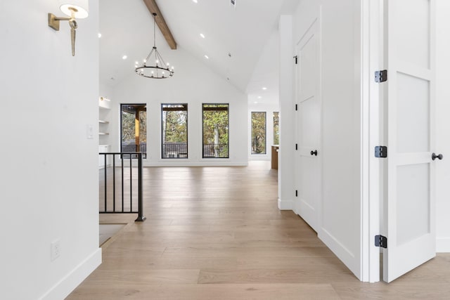 corridor featuring high vaulted ceiling, beam ceiling, light hardwood / wood-style flooring, an inviting chandelier, and built in features