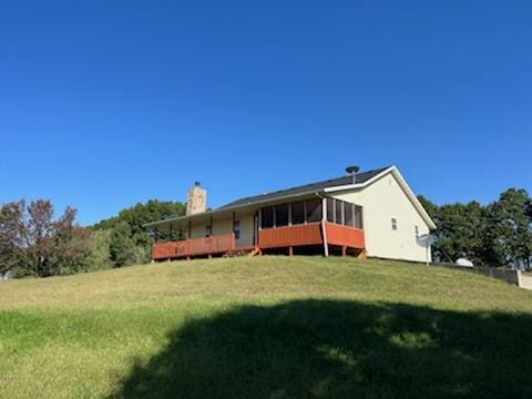 back of property featuring a sunroom and a lawn