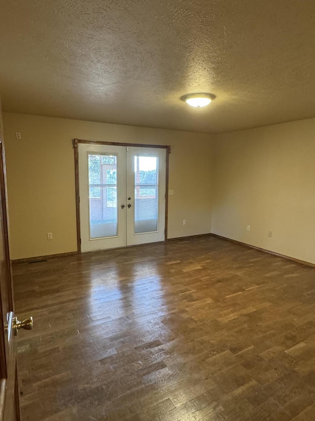 empty room with french doors, dark hardwood / wood-style flooring, and a textured ceiling