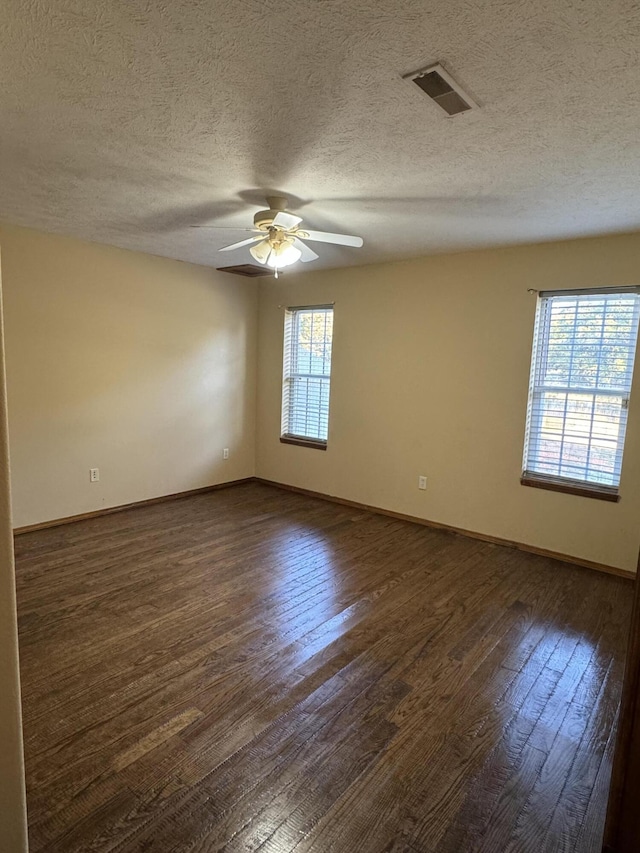 empty room with a healthy amount of sunlight, ceiling fan, and dark hardwood / wood-style flooring