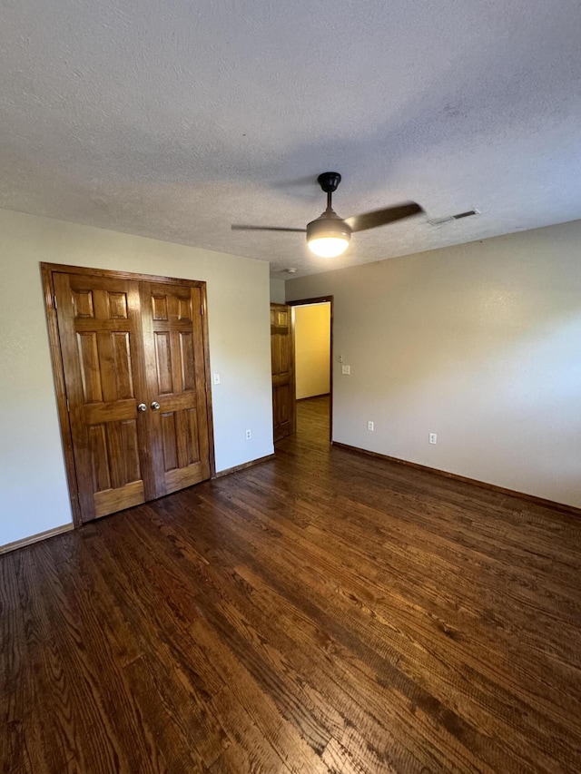 unfurnished bedroom with dark wood-type flooring, a textured ceiling, and ceiling fan