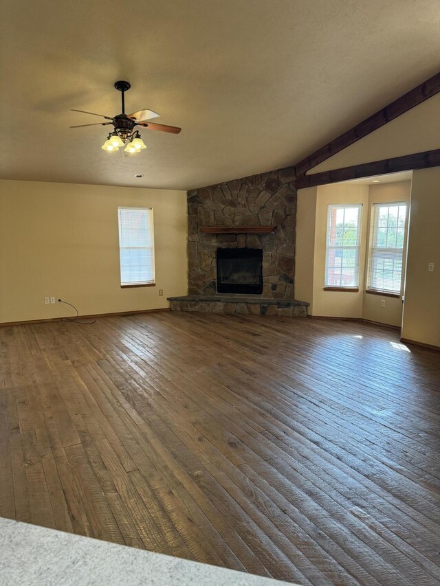 unfurnished living room with ceiling fan, dark hardwood / wood-style flooring, a stone fireplace, and lofted ceiling