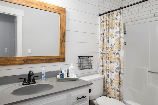 bathroom featuring vanity, wooden walls, and toilet