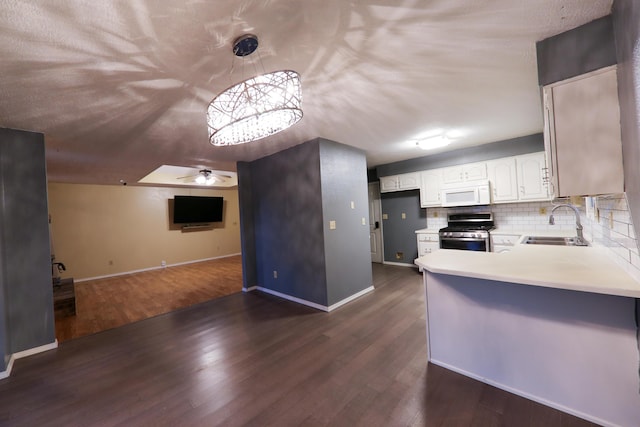 kitchen with gas stove, kitchen peninsula, pendant lighting, dark wood-type flooring, and white cabinets