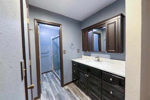 bathroom featuring hardwood / wood-style flooring, a shower with door, and vanity