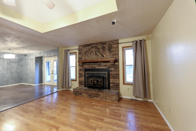 unfurnished living room featuring wood-type flooring, a brick fireplace, and a textured ceiling