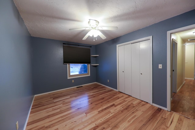 unfurnished bedroom featuring ceiling fan, light wood-type flooring, a closet, and a textured ceiling