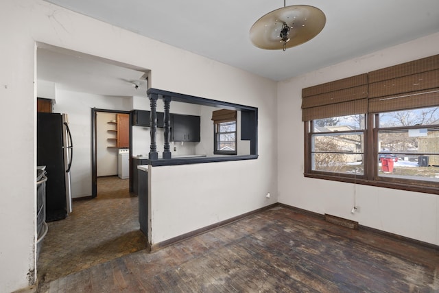 kitchen featuring stainless steel refrigerator, dark wood-type flooring, washer / clothes dryer, and a wealth of natural light