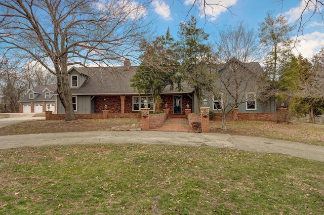 view of front of property with driveway, a shingled roof, a front lawn, a garage, and brick siding