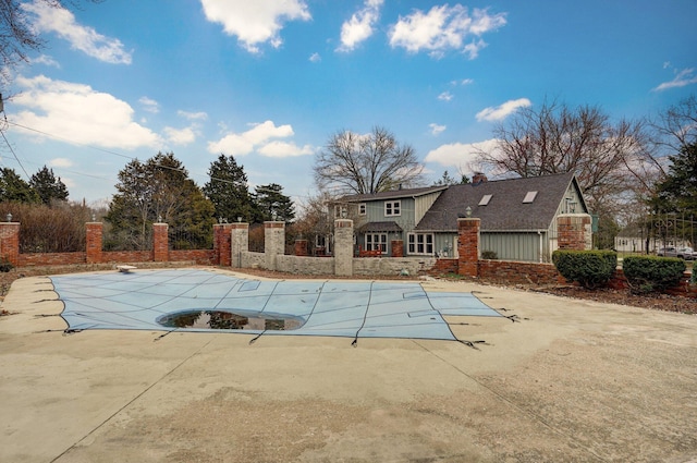 view of swimming pool featuring a covered pool, a patio area, and fence