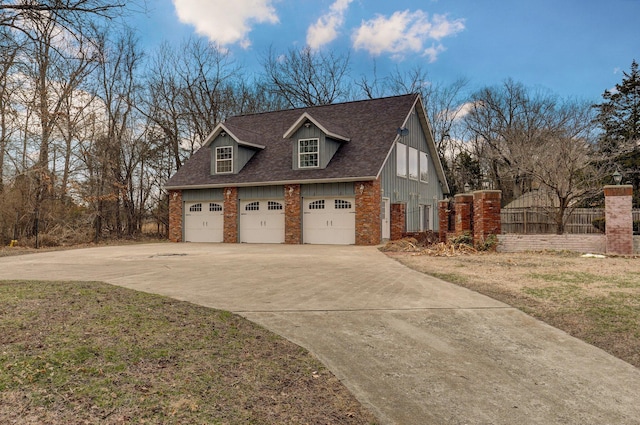 view of side of home with driveway, fence, roof with shingles, an attached garage, and brick siding