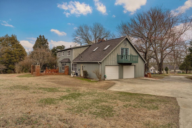 view of front of property with roof with shingles, driveway, a chimney, a front lawn, and a garage