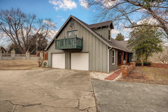 view of home's exterior with board and batten siding, roof with shingles, concrete driveway, and a balcony