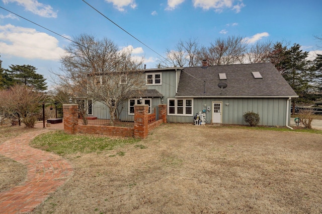 rear view of house with a lawn, a chimney, and a shingled roof