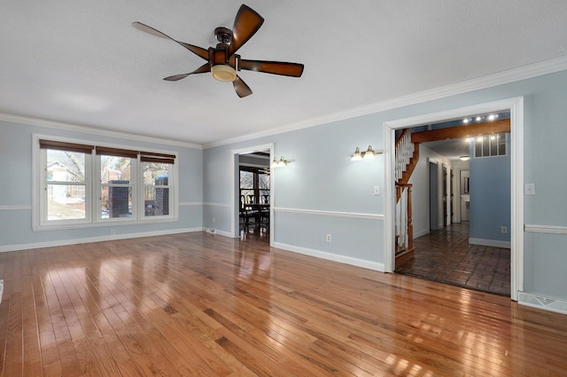 unfurnished room featuring baseboards, wood-type flooring, stairs, and crown molding