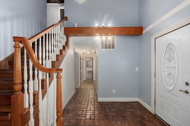 foyer featuring stairs, brick floor, visible vents, and baseboards