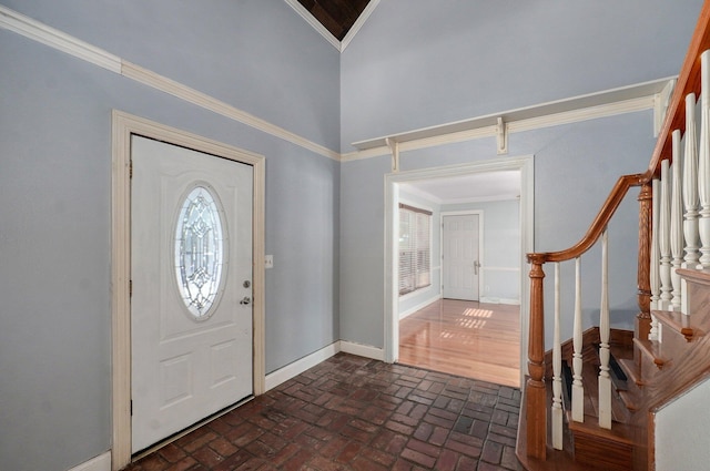 entryway with baseboards, stairway, ornamental molding, a high ceiling, and brick floor