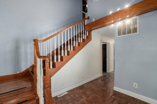 stairway featuring brick floor, visible vents, and baseboards