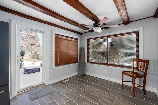 interior space featuring a wealth of natural light, beamed ceiling, baseboards, and a ceiling fan